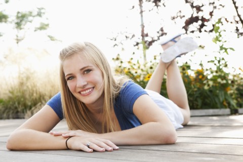 Smiling Caucasian teenager laying on deck
