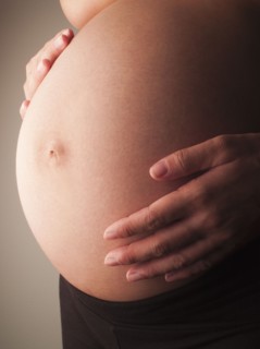 Mixed race woman holding pregnant stomach