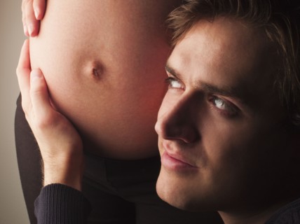 Husband listening to pregnant wife's stomach
