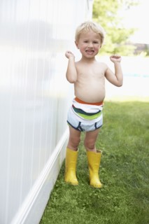 Caucasian boy wearing diaper and rain boots outdoors