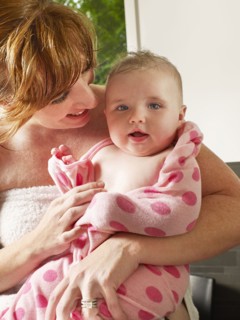 Mother wrapping baby girl in towel