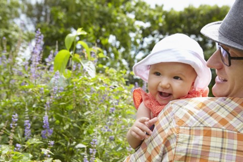 Father carrying baby daughter in park