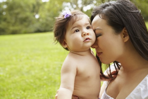 Mother cradling baby girl in park