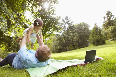 Father playing with baby girl in park