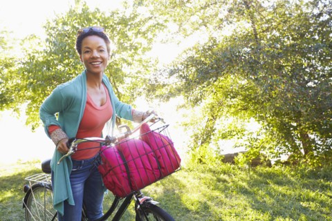 Black woman pushing bicycle outdoors