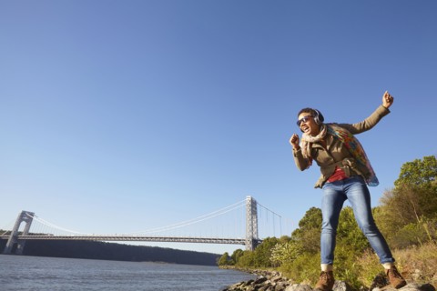 Black woman listening to headphones at river