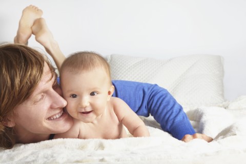 Father and baby laying on blanket