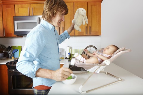 Father playing with baby in chair