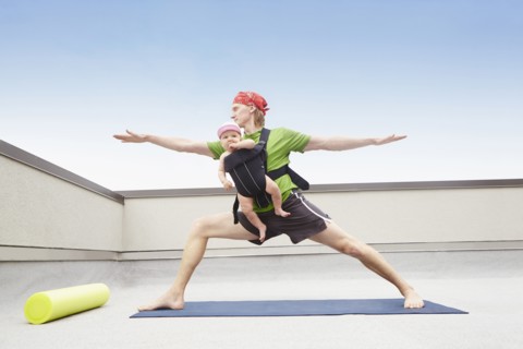 Father practicing yoga and holding baby