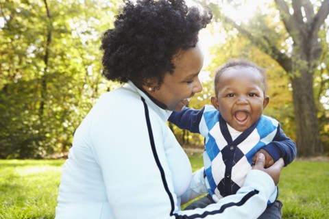 Black mother and toddler son playing in park