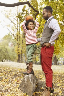 Father and son holding pumpkin in park
