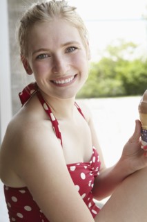 Smiling woman in swimsuit eating ice cream cone