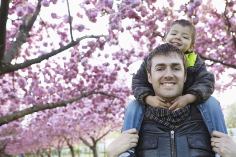 Father carrying son on shoulders in park
