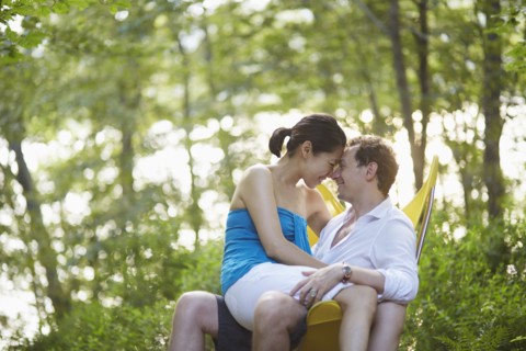 Couple rubbing noses on bench in park