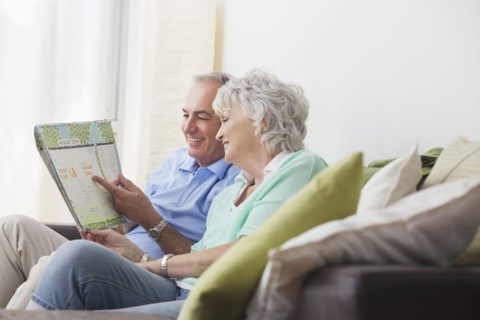 Older couple reading paperwork on sofa