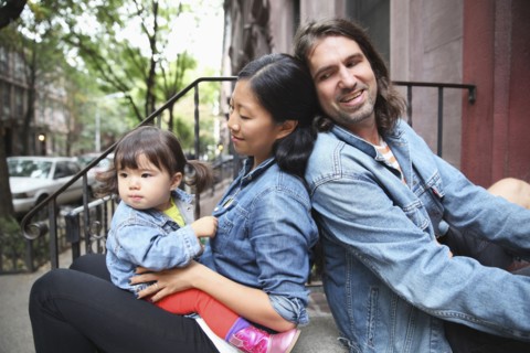 Family sitting on front stoop in city