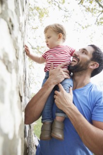Caucasian father holding baby son under tree