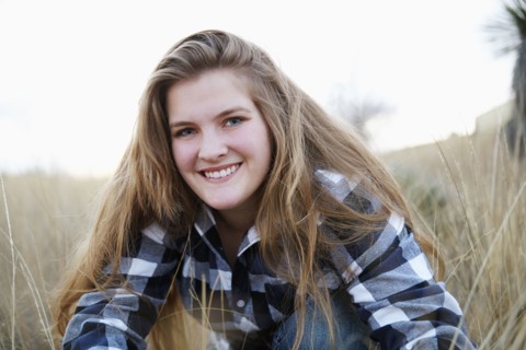 Smiling woman sitting in tall grass