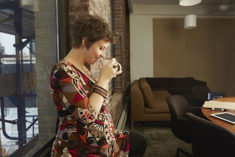 Pregnant businesswoman drinking coffee in office