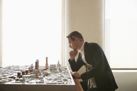 Caucasian architect examining urban model in office