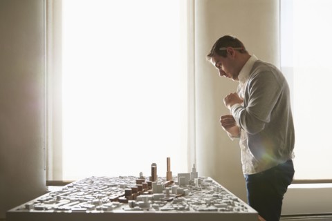 Caucasian architect examining urban model in office