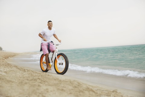 Black man riding bicycle on beach