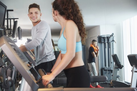 Couple using exercise machines in gym