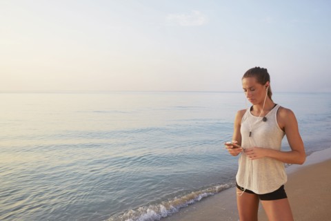 Athlete listening to earphones on beach