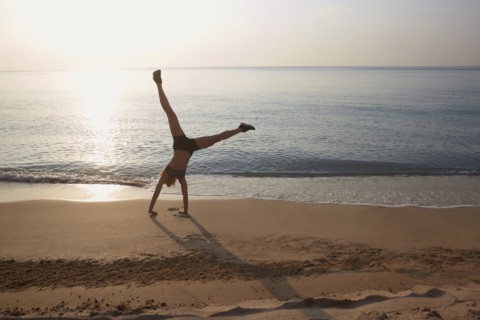 Athlete doing cartwheel on beach