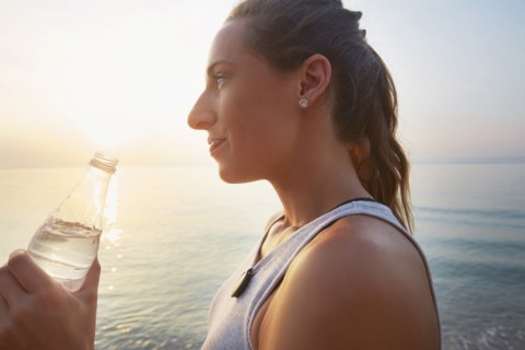 Athlete drinking water bottle on beach