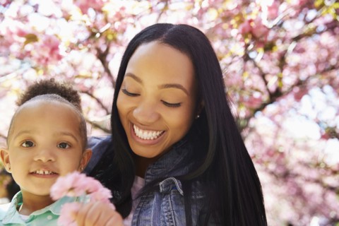 Mother and daughter under flowering tree in park