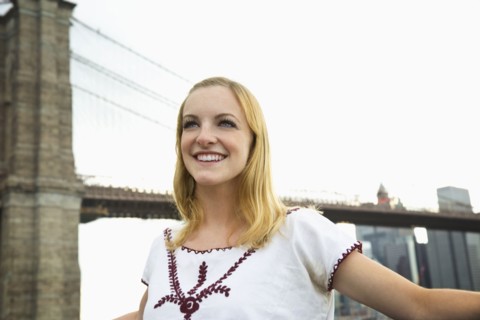 Caucasian woman smiling under Brooklyn Bridge