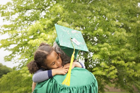 College graduate father hugging daughter