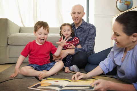 Family reading book on floor in living room