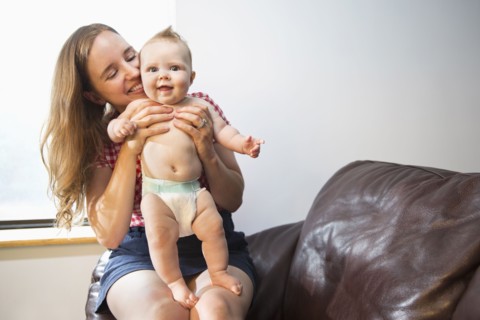 Caucasian mother holding baby daughter in armchair