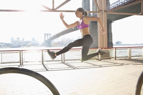 Caucasian runner jumping on waterfront