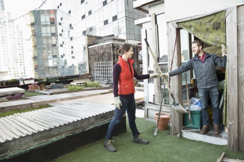 Couple holding gardening tools on urban rooftop
