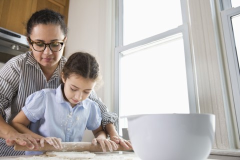 Mother teaching daughter to bake in kitchen