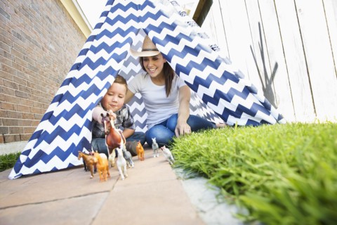 Caucasian mother and son in teepee playing with toy horses
