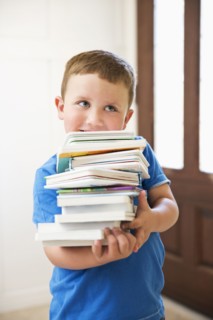 Caucasian boy carrying stack of books