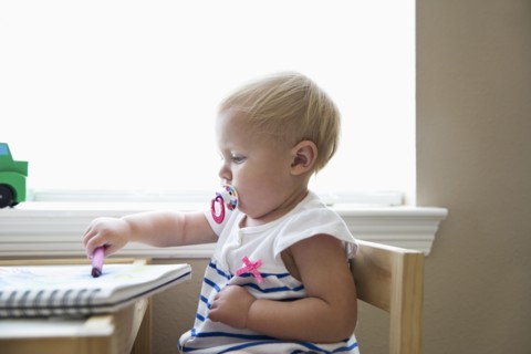 Caucasian baby girl drawing with crayon