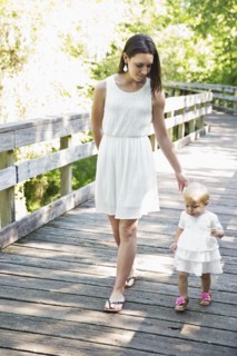 Caucasian mother and baby daughter walking on wooden footbridge