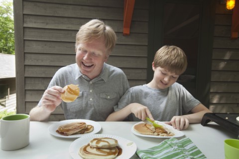 Caucasian father and son eating pancakes outdoors