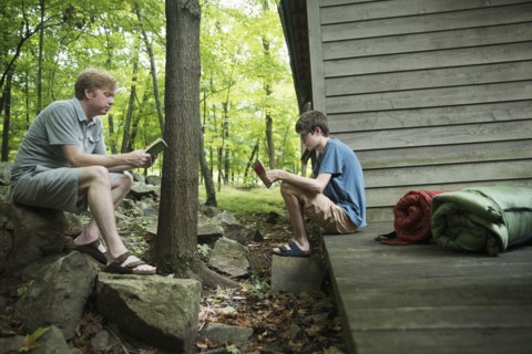 Caucasian father and son reading books at cabin