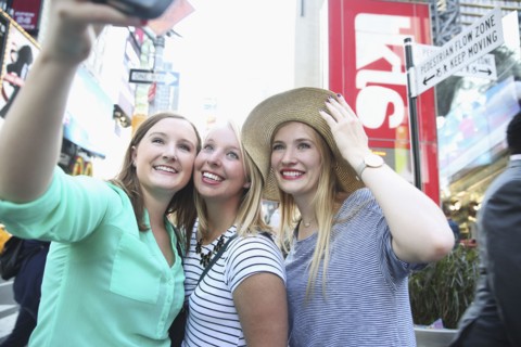 Smiling Caucasian woman posing for cell phone selfie in city