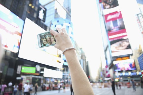 Arm of Caucasian woman posing for cell phone selfie with friends