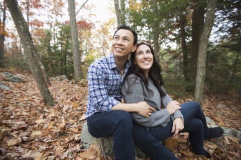 Couple sitting on rock in forest during autumn
