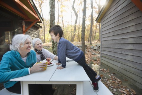 Grandmothers enjoying breakfast outdoors near cabin with grandson