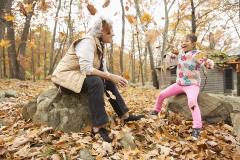 Grandmother and granddaughter playing with autumn leaves