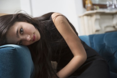 Pensive Caucasian girl resting head on armchair